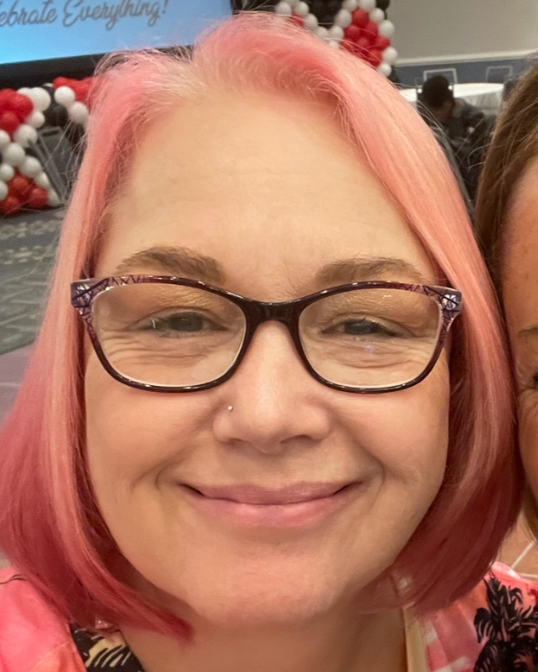 Amy, Lead balloon stylist at Boston Balloon Art with pink hair and glasses smiling.