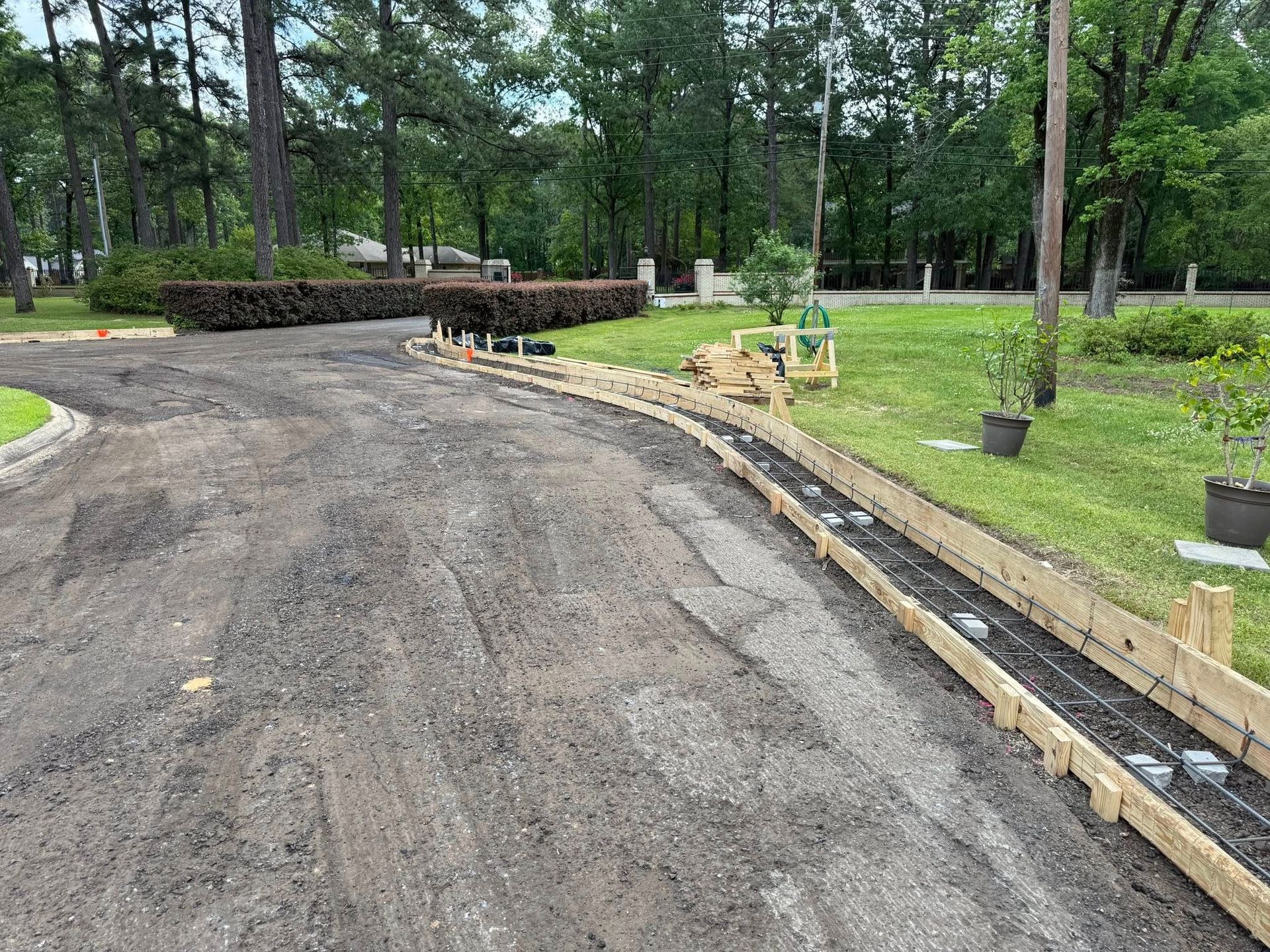 A driveway is being built in a yard with trees in the background.