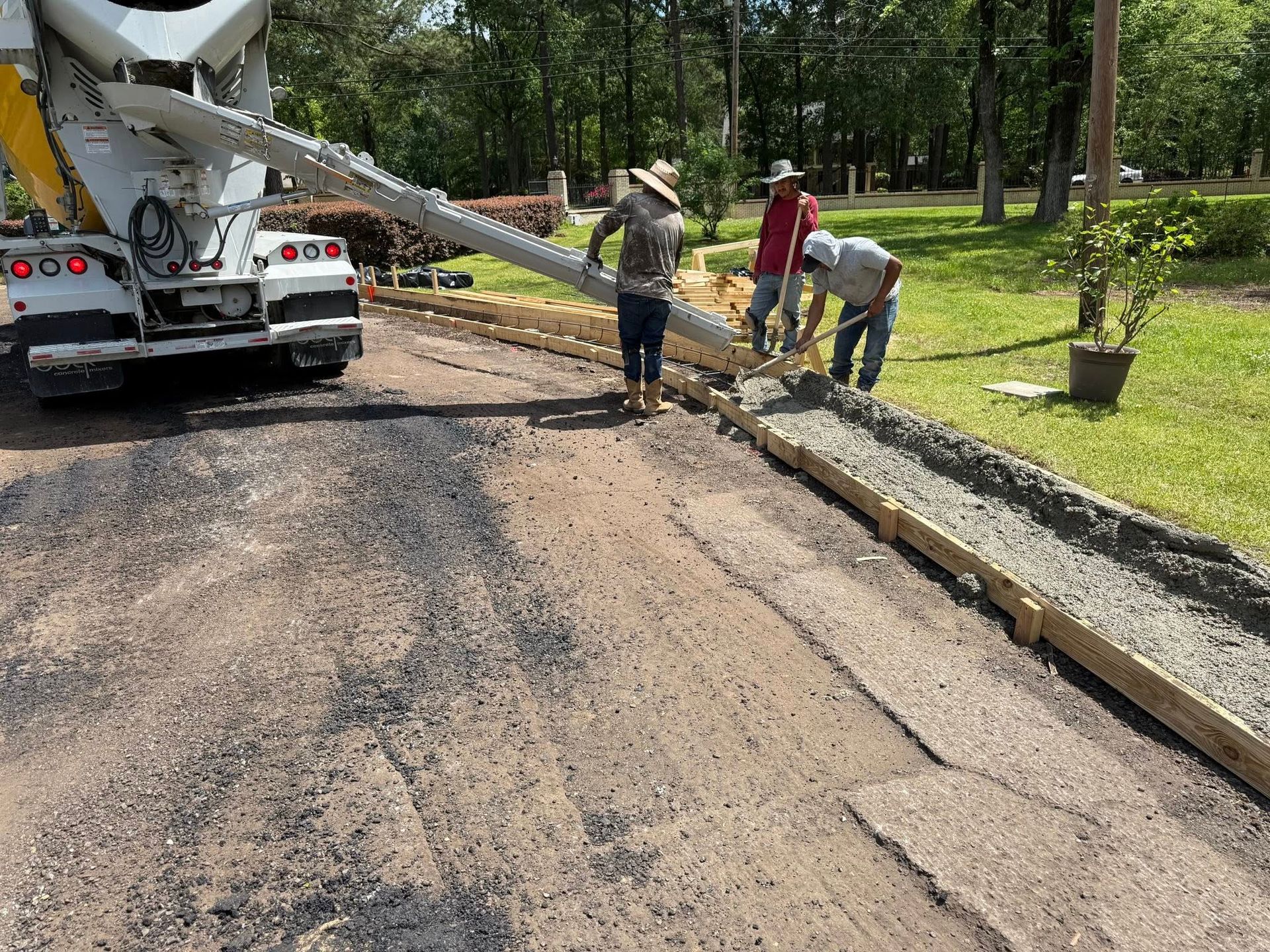 A concrete truck is pouring concrete into a driveway.