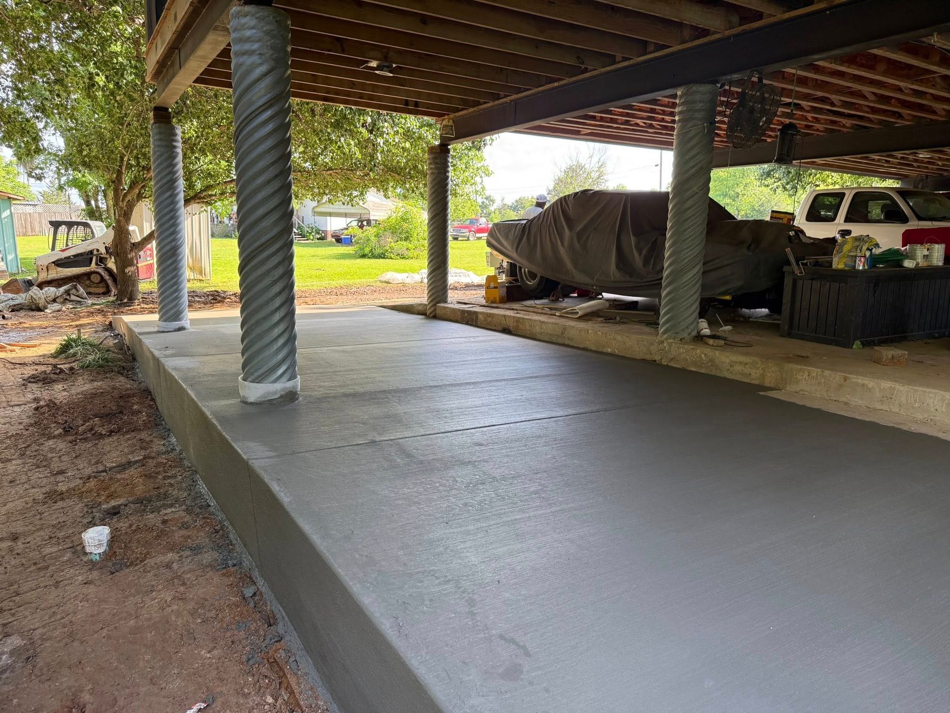 A car is parked under a deck in a garage.