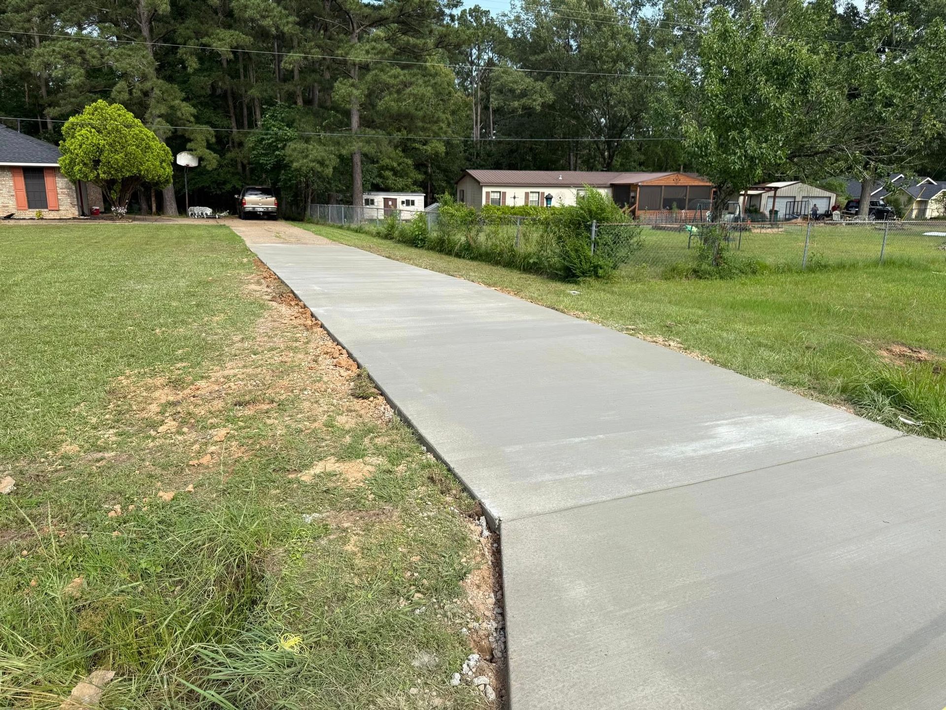 A concrete walkway going through a grassy field.