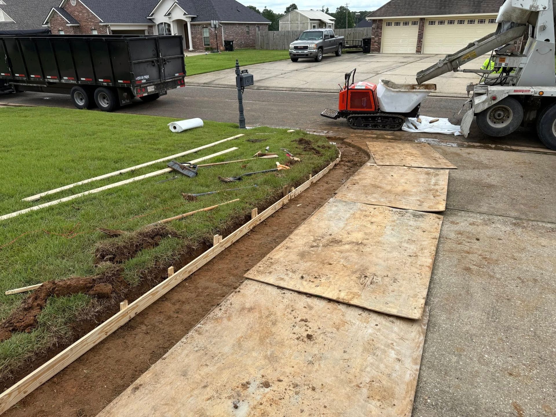 A concrete mixer is being used to pour concrete into a driveway.
