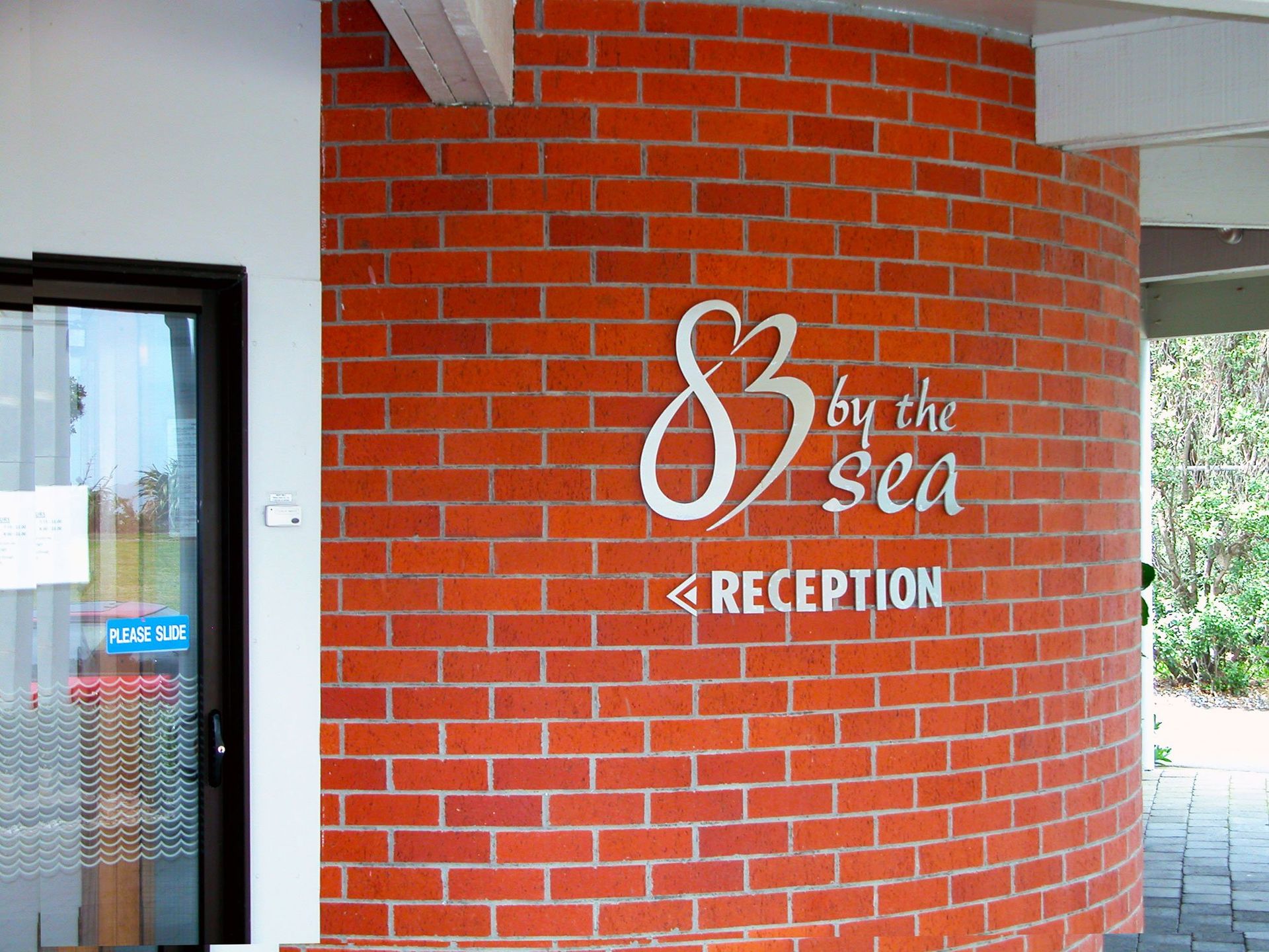 5mm thick router cut aluminium letters with pins in the back of each letter installed onto curved external concrete wall
