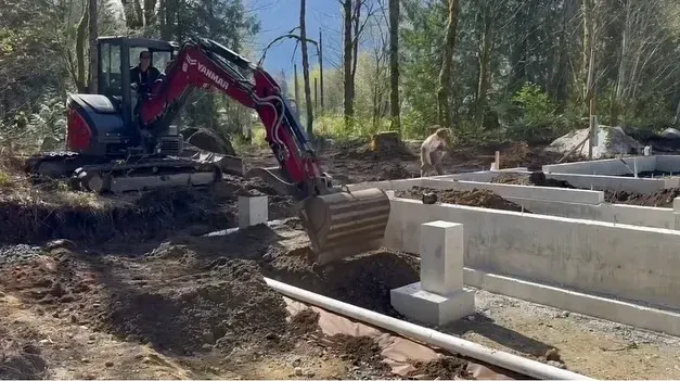 A large orange excavator is sitting on top of a dirt field.