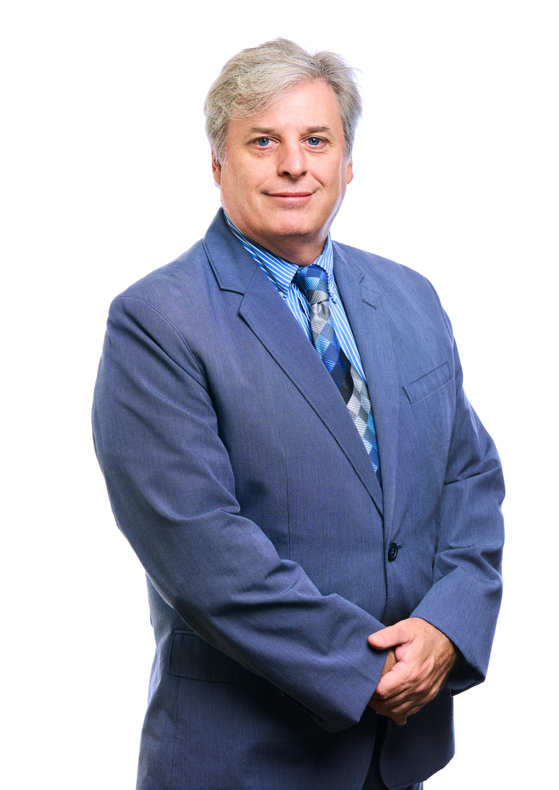 A man in a blue suit and tie is standing with his arms crossed.