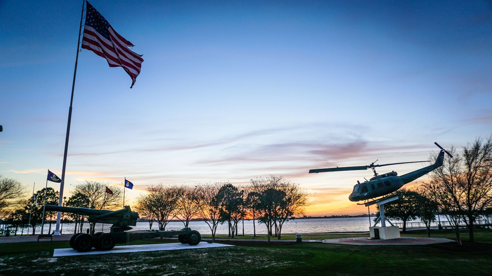An american flag is flying in the wind next to a helicopter.