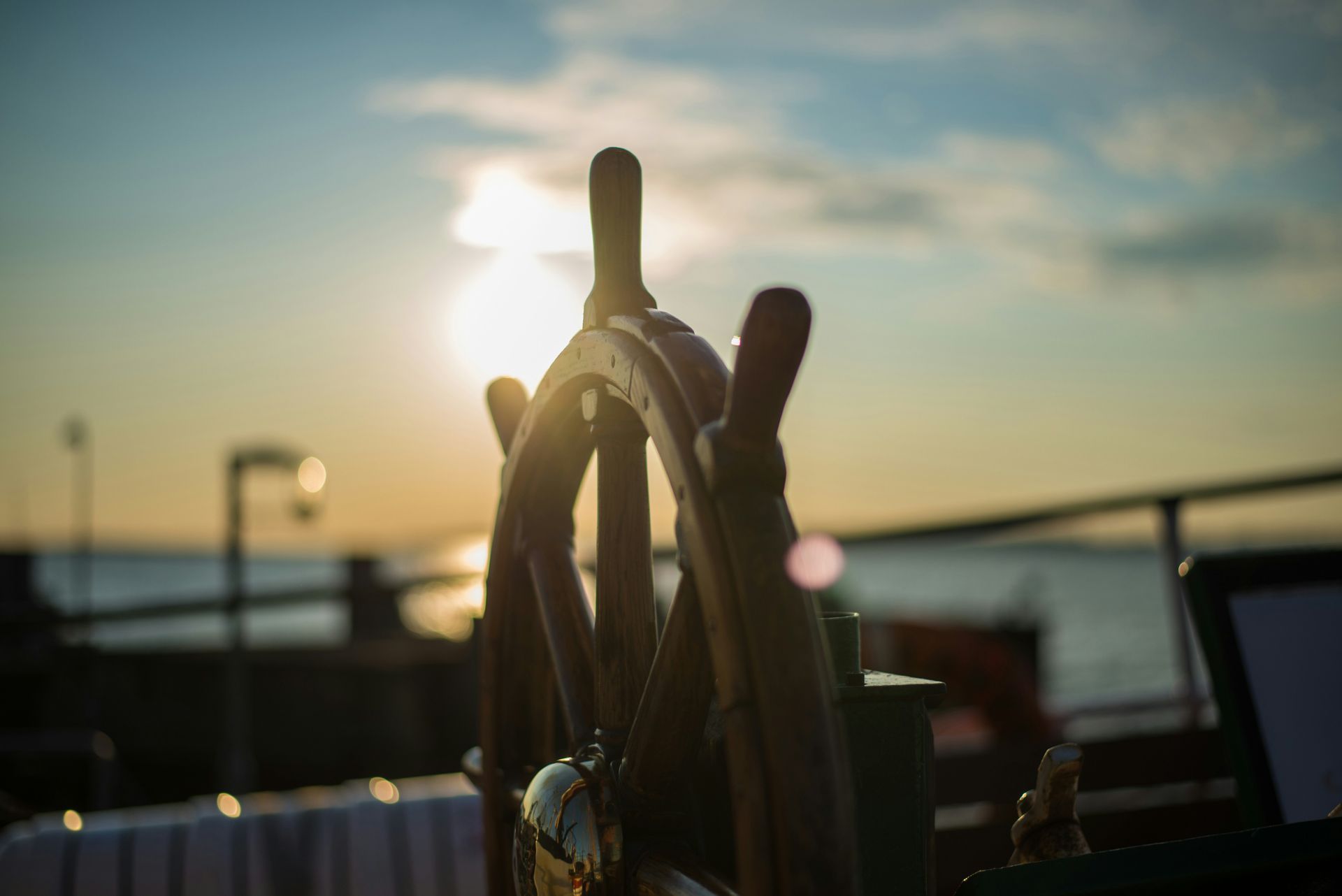 A steering wheel on a boat with the sun shining through it.