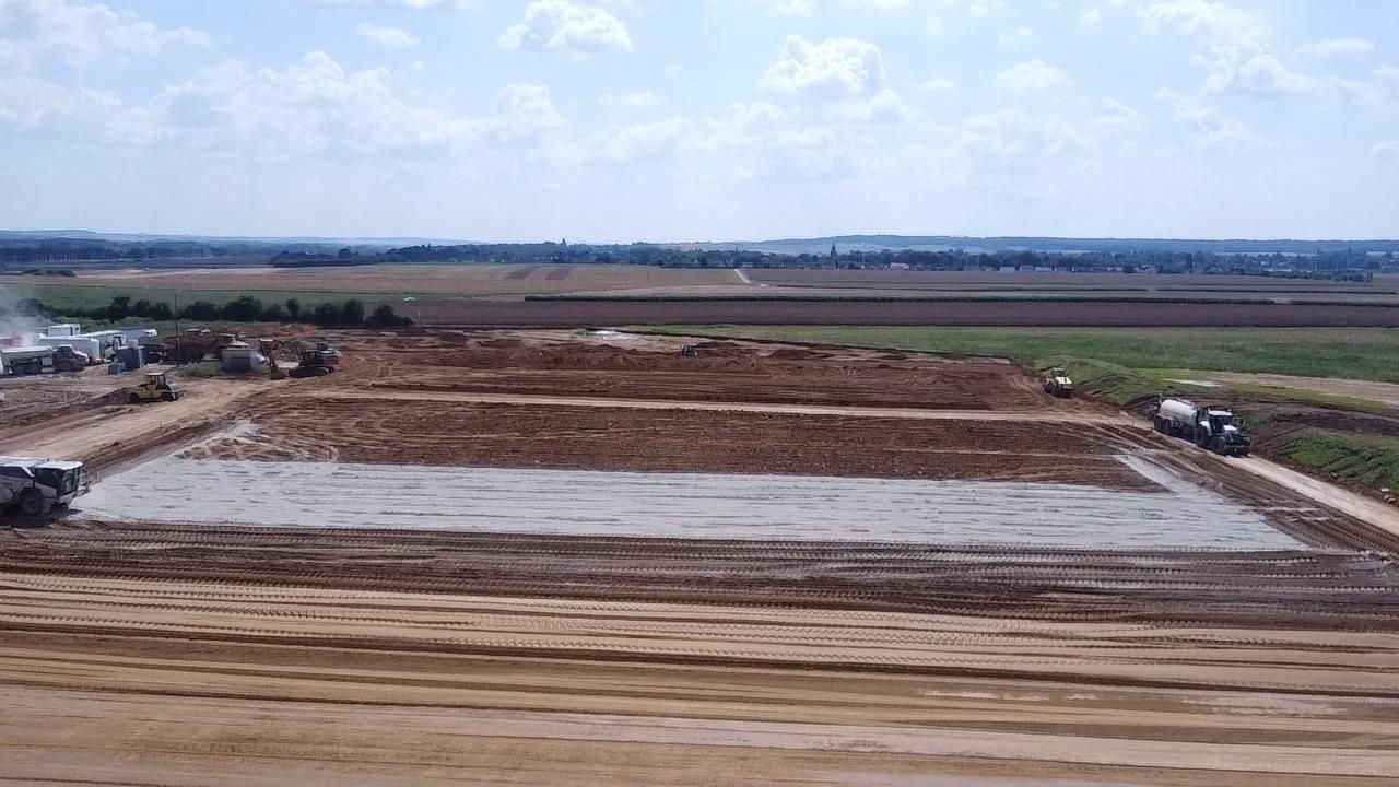 Une vue aérienne d'un chantier de construction avec une grande dalle de béton au milieu d'un champ de terre.