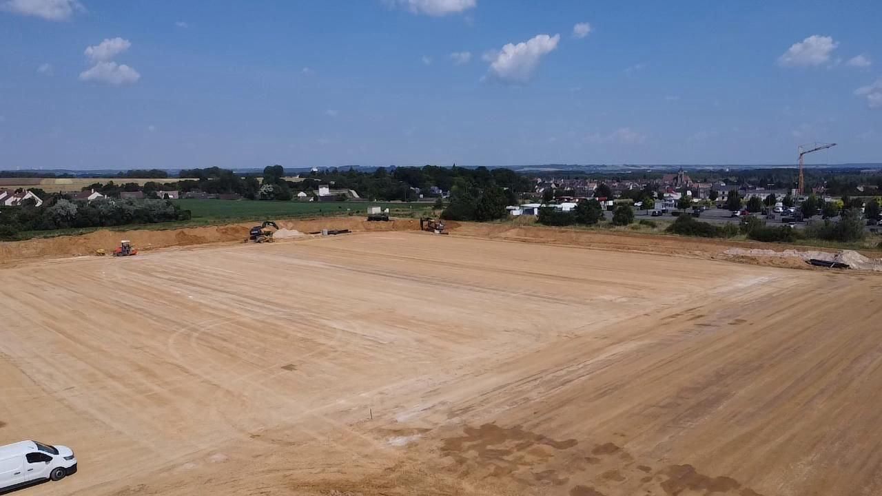 Une vue aérienne d'un champ de terre avec un camion garé au milieu.