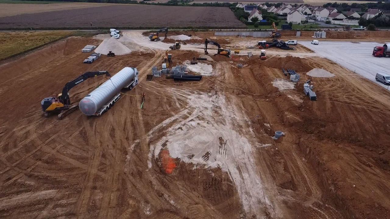 Une vue aérienne d'un chantier de construction avec un grand réservoir au milieu.