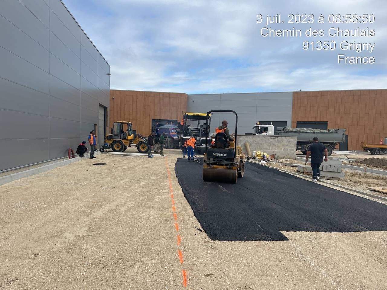 Un groupe de personnes travaille sur une route devant un grand bâtiment.