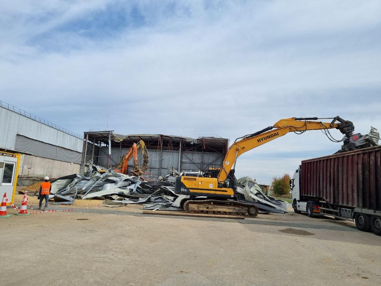 Une grande excavatrice jaune est en train de démolir un bâtiment.