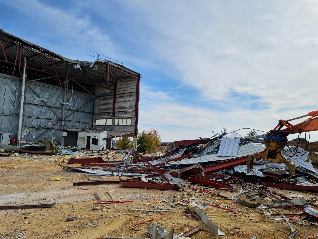 Un grand bâtiment est en train d'être démoli par un bulldozer.
