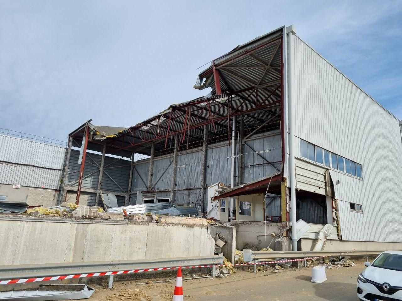 Une camionnette blanche est garée devant un immeuble en cours de démolition.