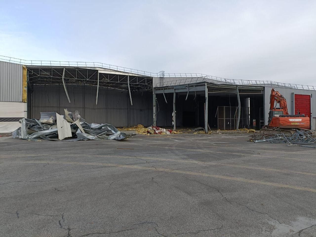 Un grand bâtiment est en cours de démolition sur un parking.