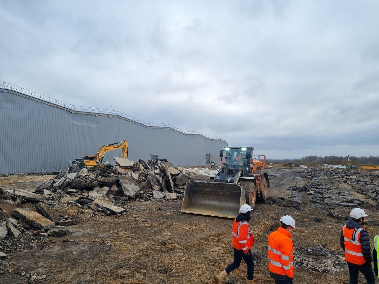 Un groupe d'ouvriers du bâtiment se tient devant un bulldozer sur un chantier de construction.