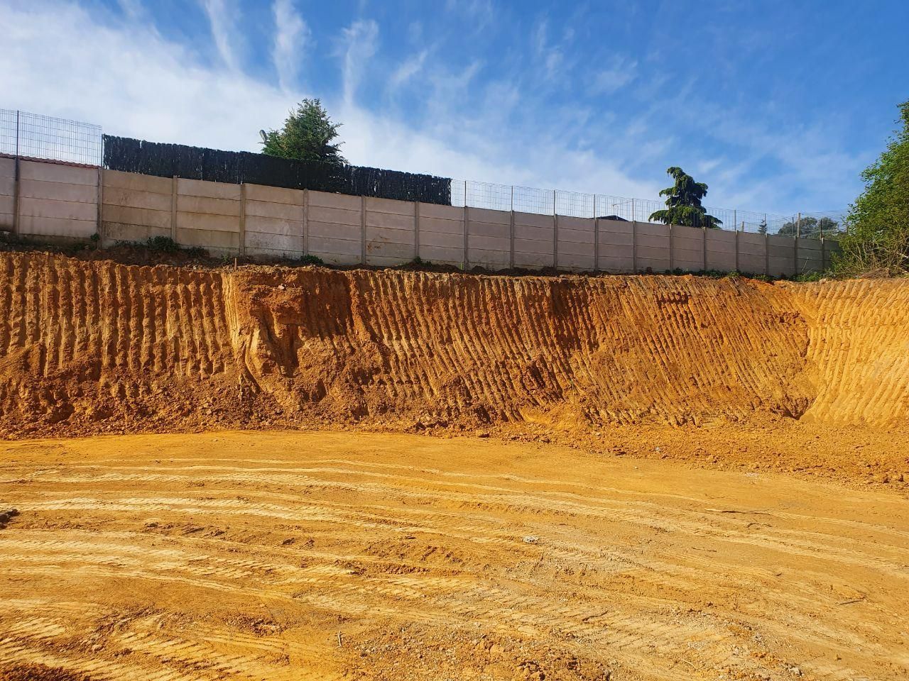 Un grand champ de terre avec une clôture de barbelés en arrière-plan.