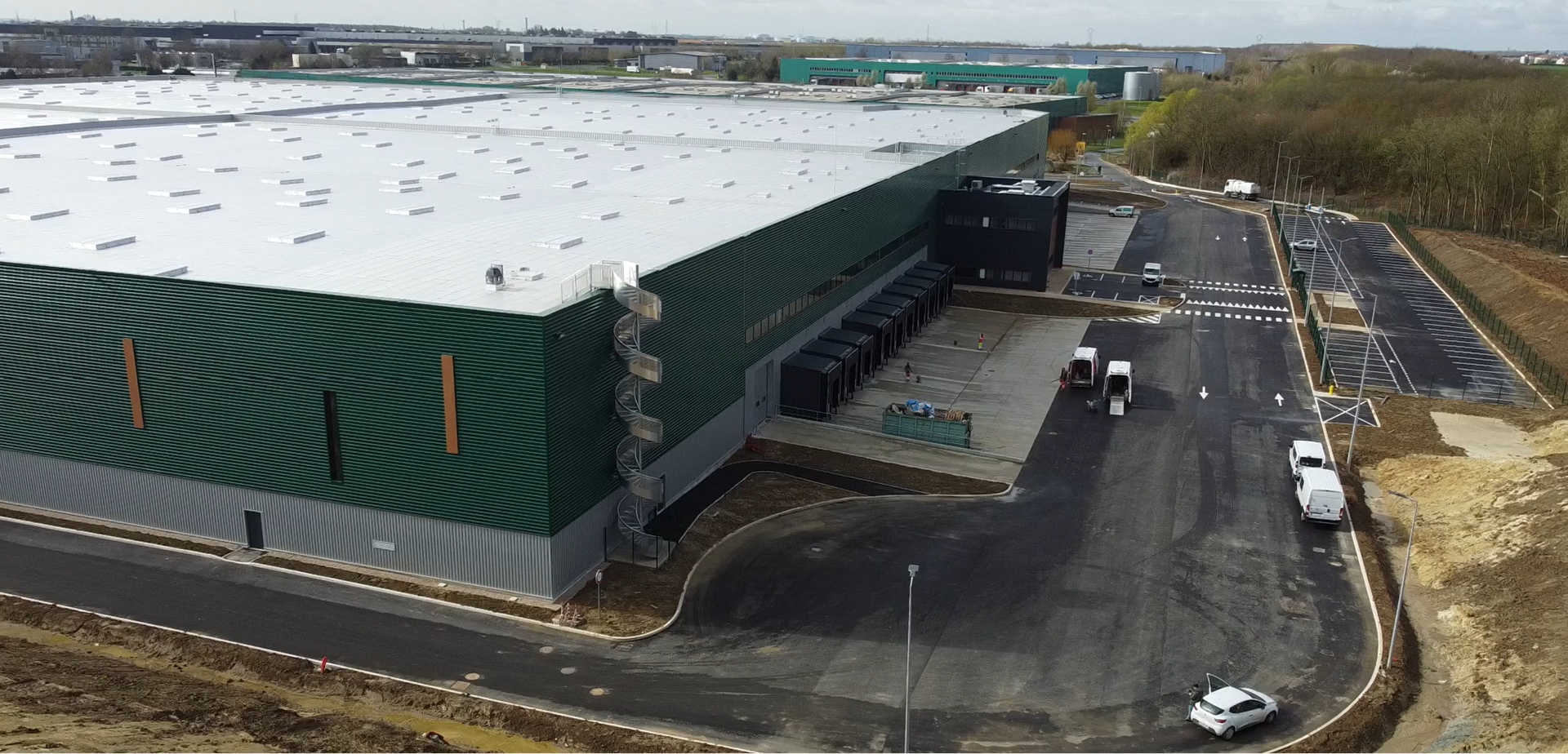 Une vue aérienne d'un grand entrepôt au toit blanc.