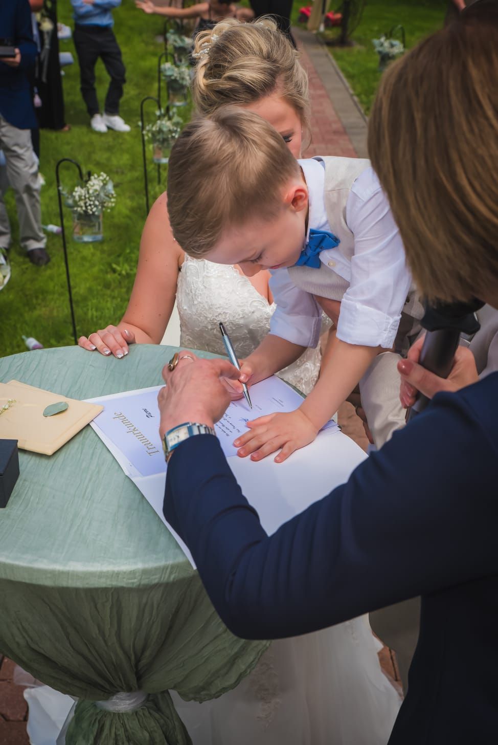 Ein Brautpaar unterschreibt mit seinen Kindern eine Heiratsurkunde.