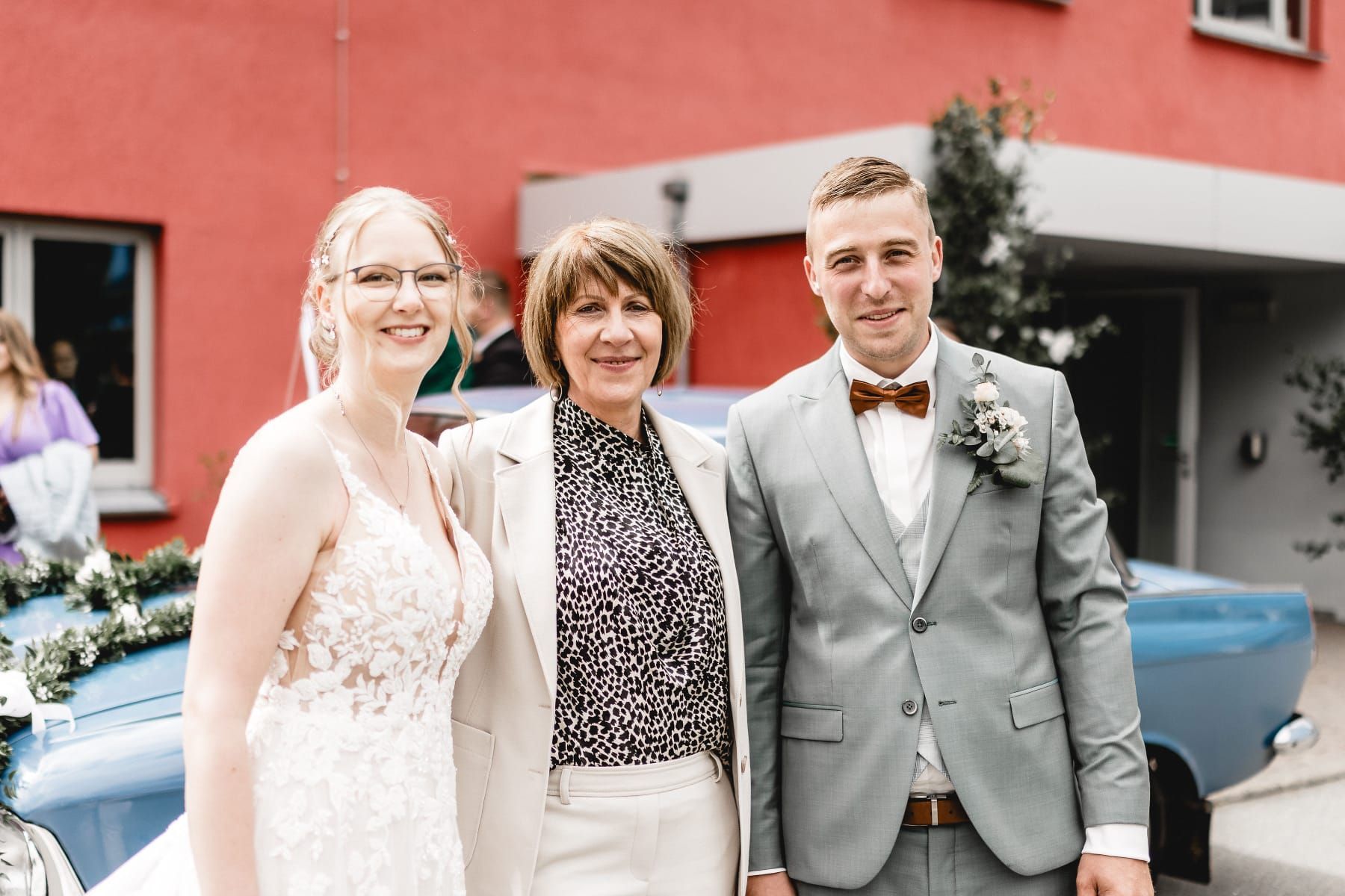 Eine Braut und ein Bräutigam posieren für ein Foto mit ihrer freien Rednerin.