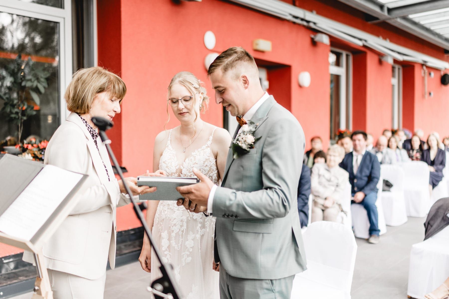 Eine Braut und ein Bräutigam halten während ihrer Hochzeitszeremonie ein Buch in der Hand.