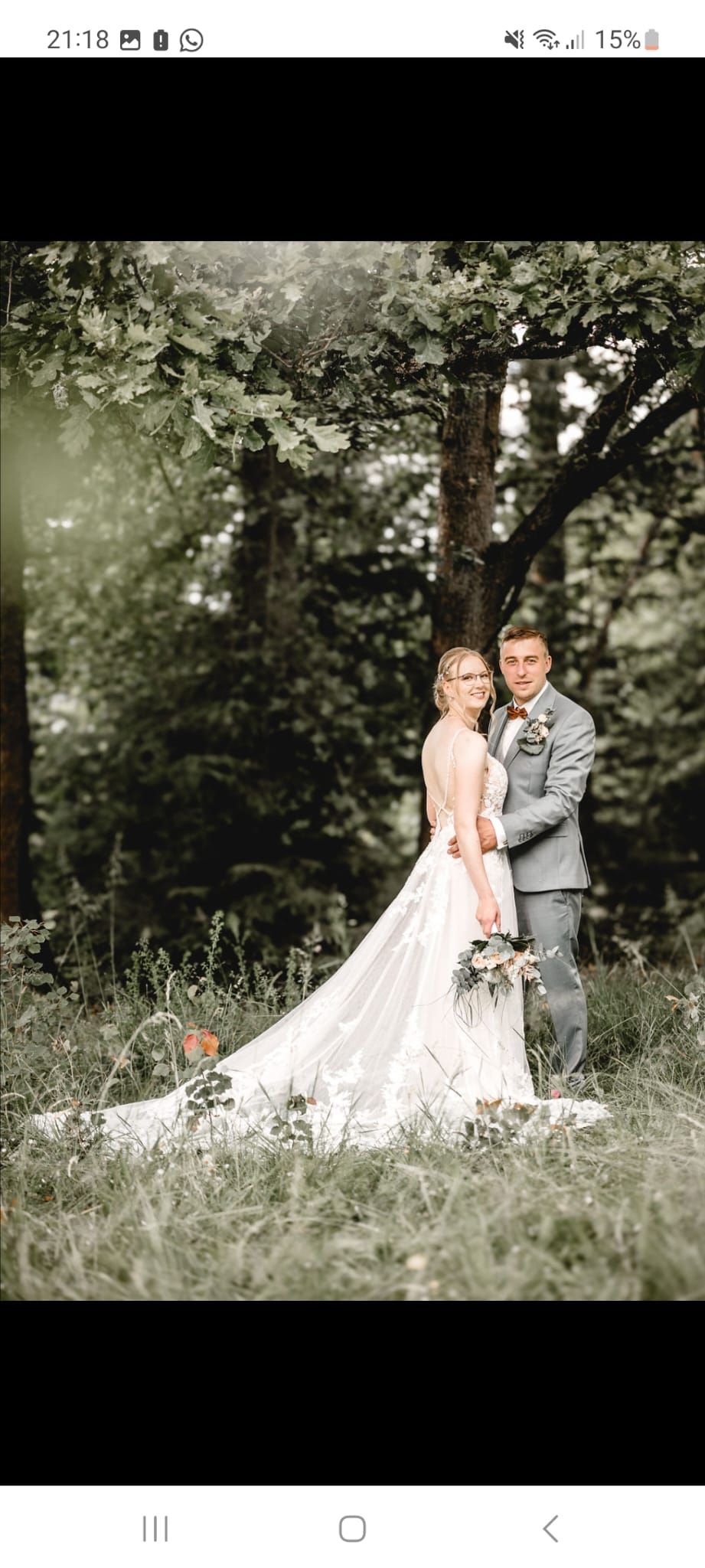 Eine Braut und ein Bräutigam posieren im Wald für ein Foto.