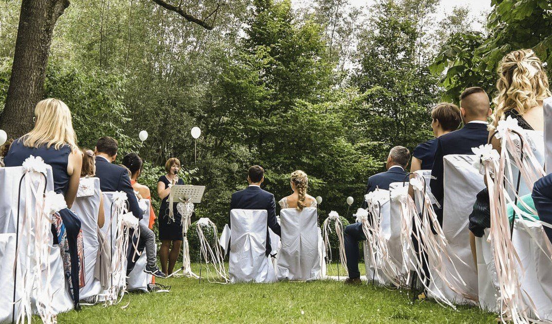Eine Gruppe von Menschen sitzt bei einer Hochzeitszeremonie auf Stühlen.