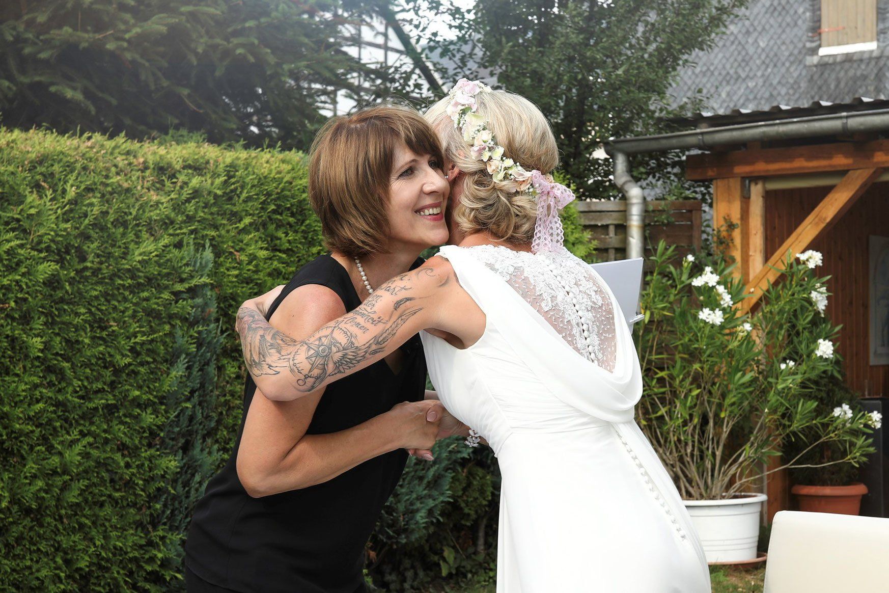 Eine Frau in einem Brautkleid umarmt eine andere Frau.