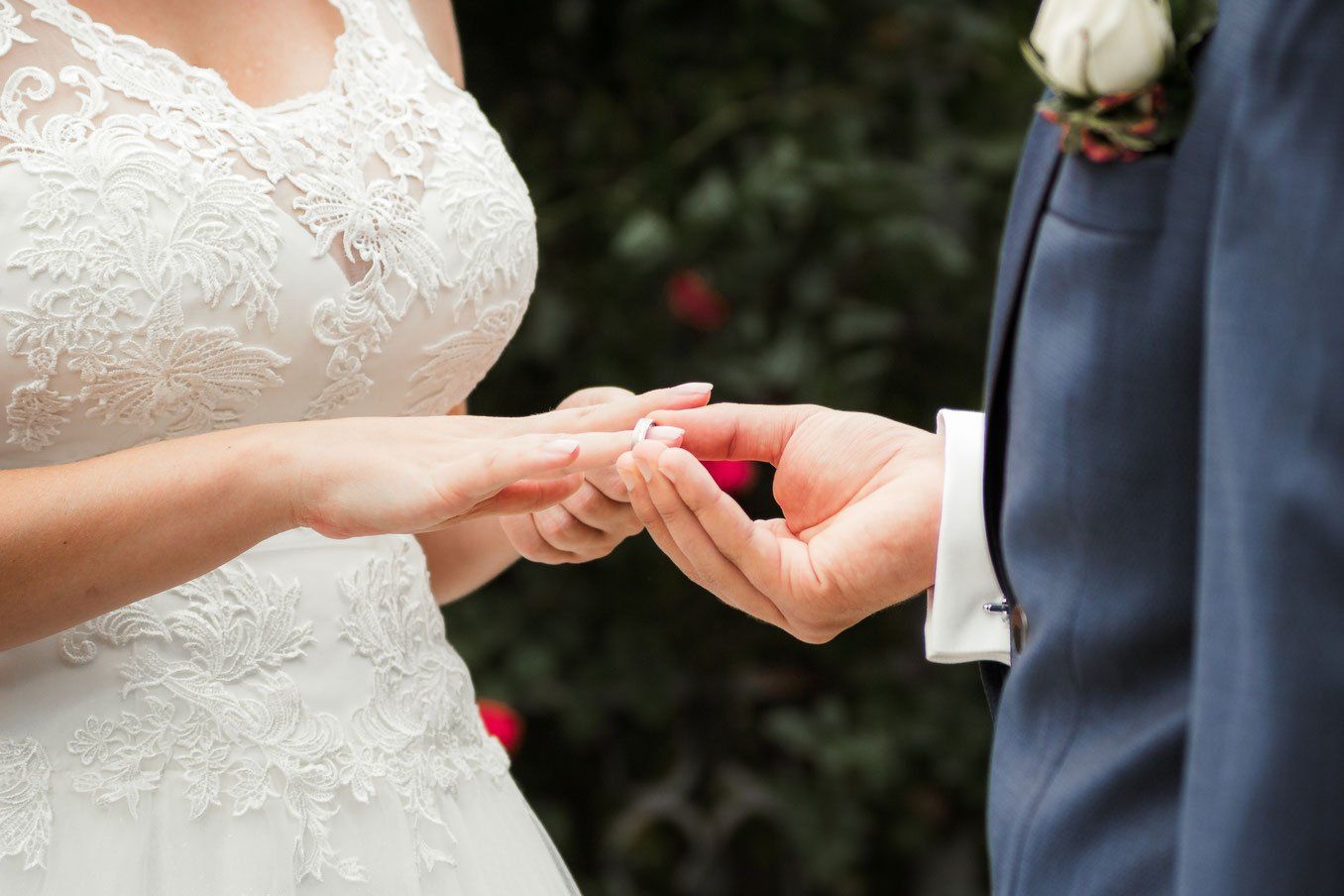 Eine Braut und ein Bräutigam heiraten und die Braut steckt dem Bräutigam einen Ehering an den Finger.