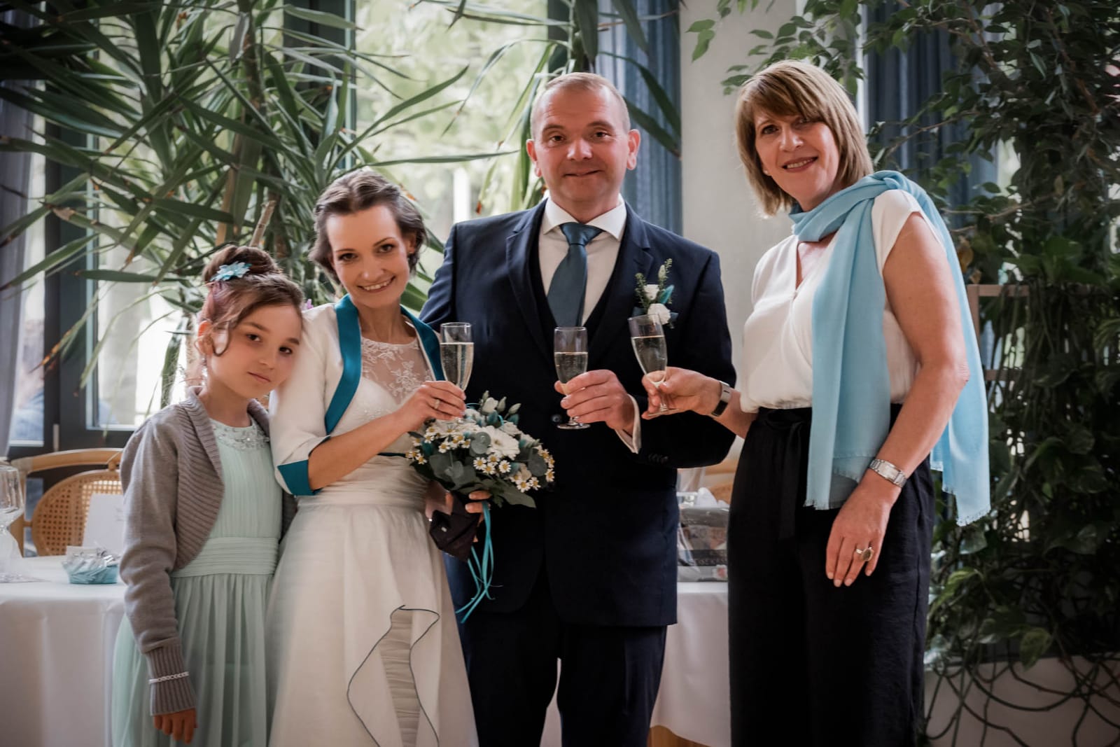 Eine Braut und ein Bräutigam posieren mit ihrer Familie und der Hochzeitsrednerin für ein Foto.