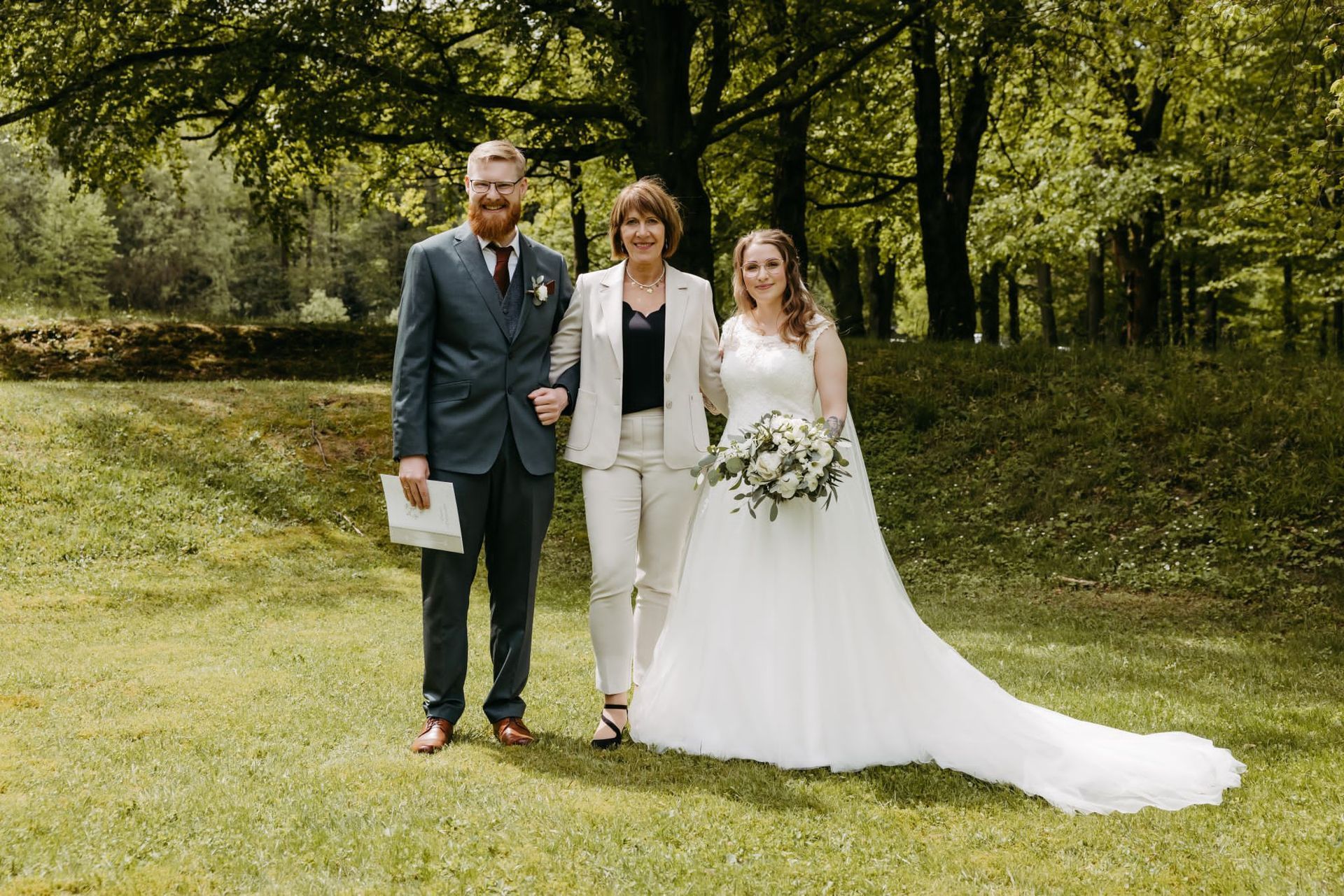 Ein Brautpaar posiert mit der freien Rednerin für ein Foto.