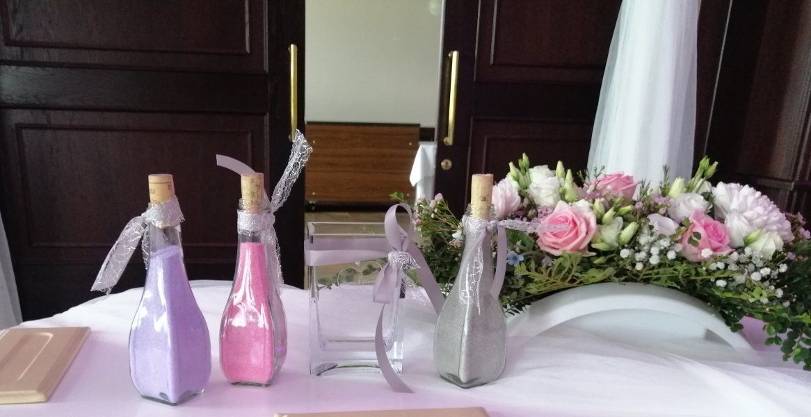 Ein Tisch mit Sandflaschen und Blumen darauf.