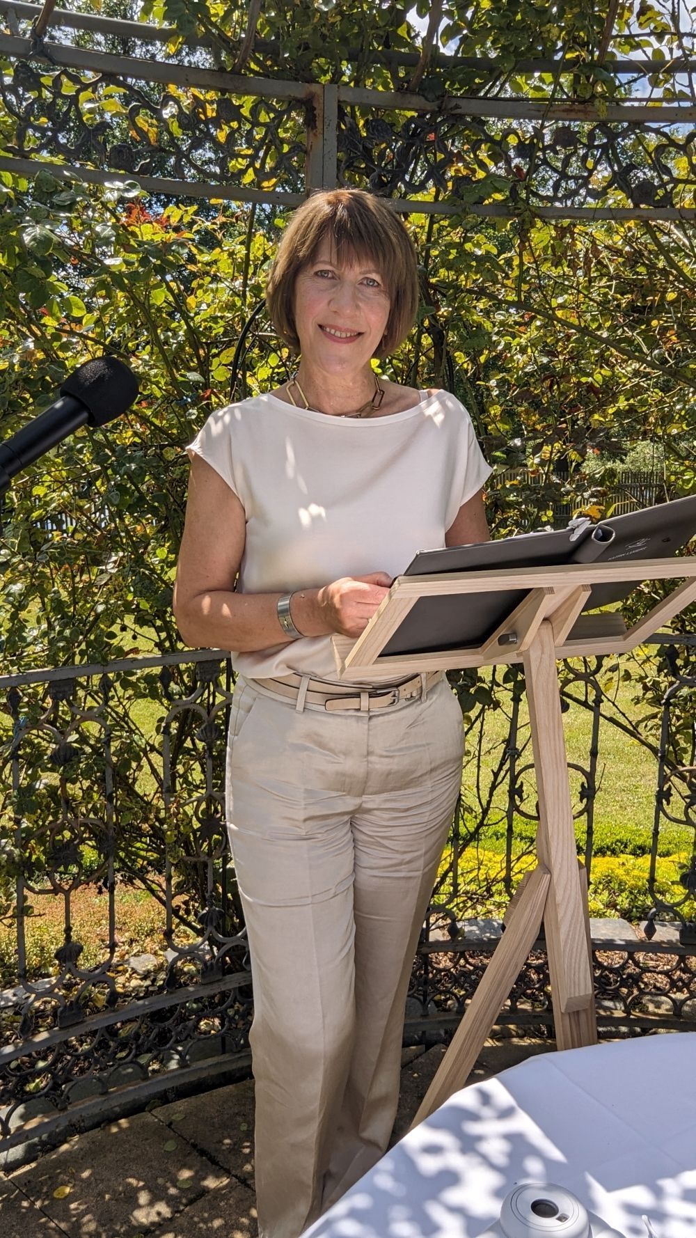 Eine Frau steht an einem Podium und hält ein Buch in der Hand.