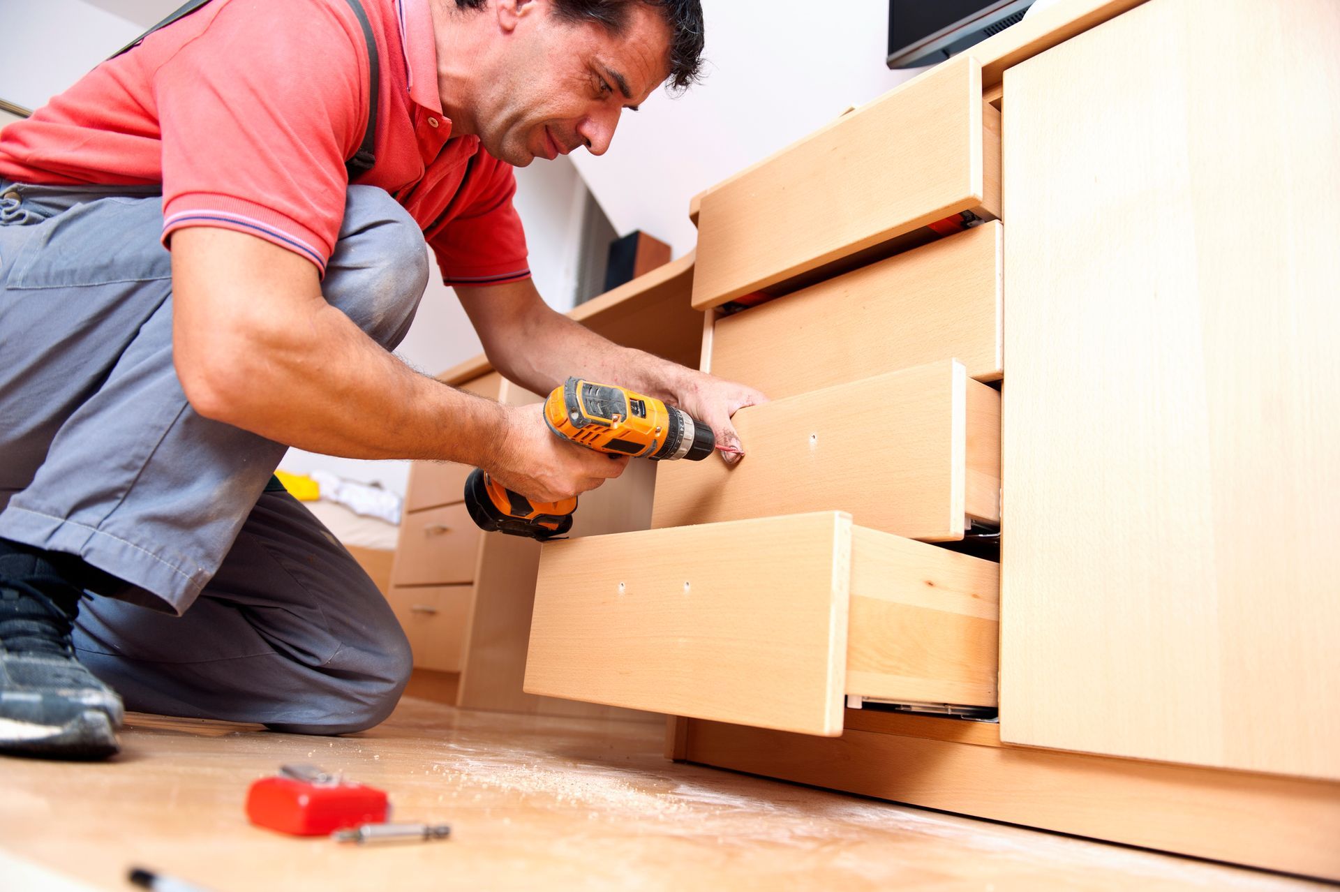 A man is using a drill to fix a drawer.