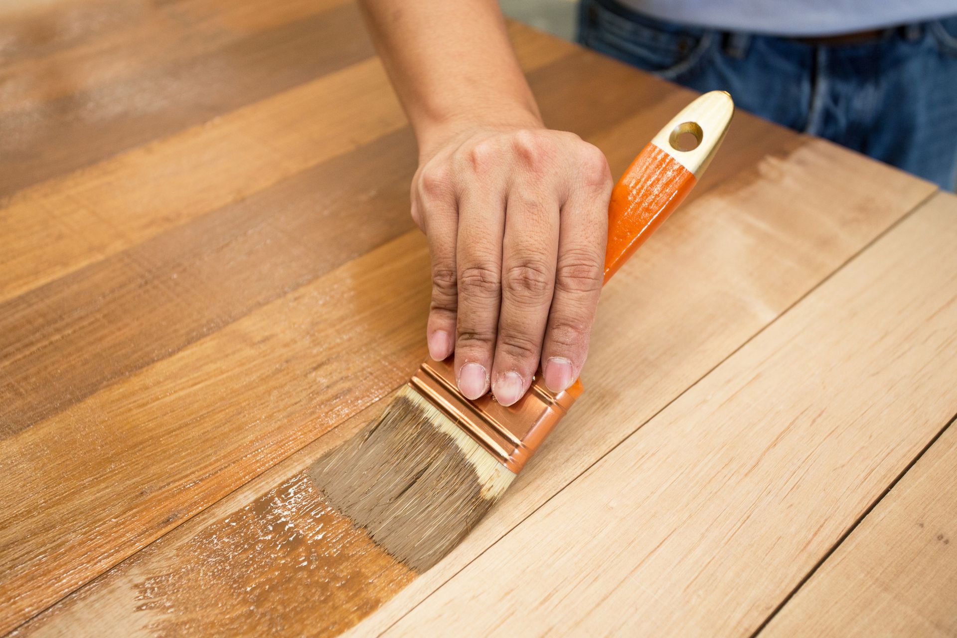 A person is painting a wooden table with a brush.