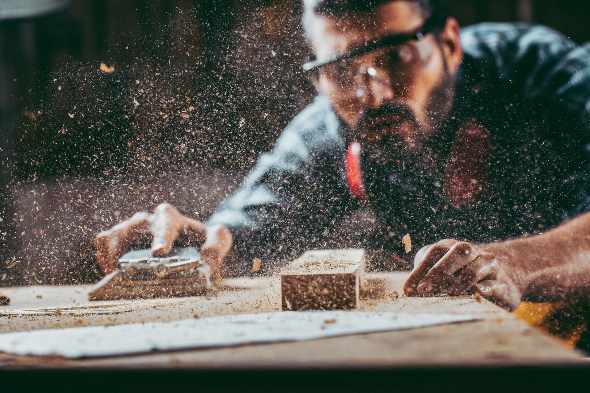 A man is sanding a piece of wood with a sander.