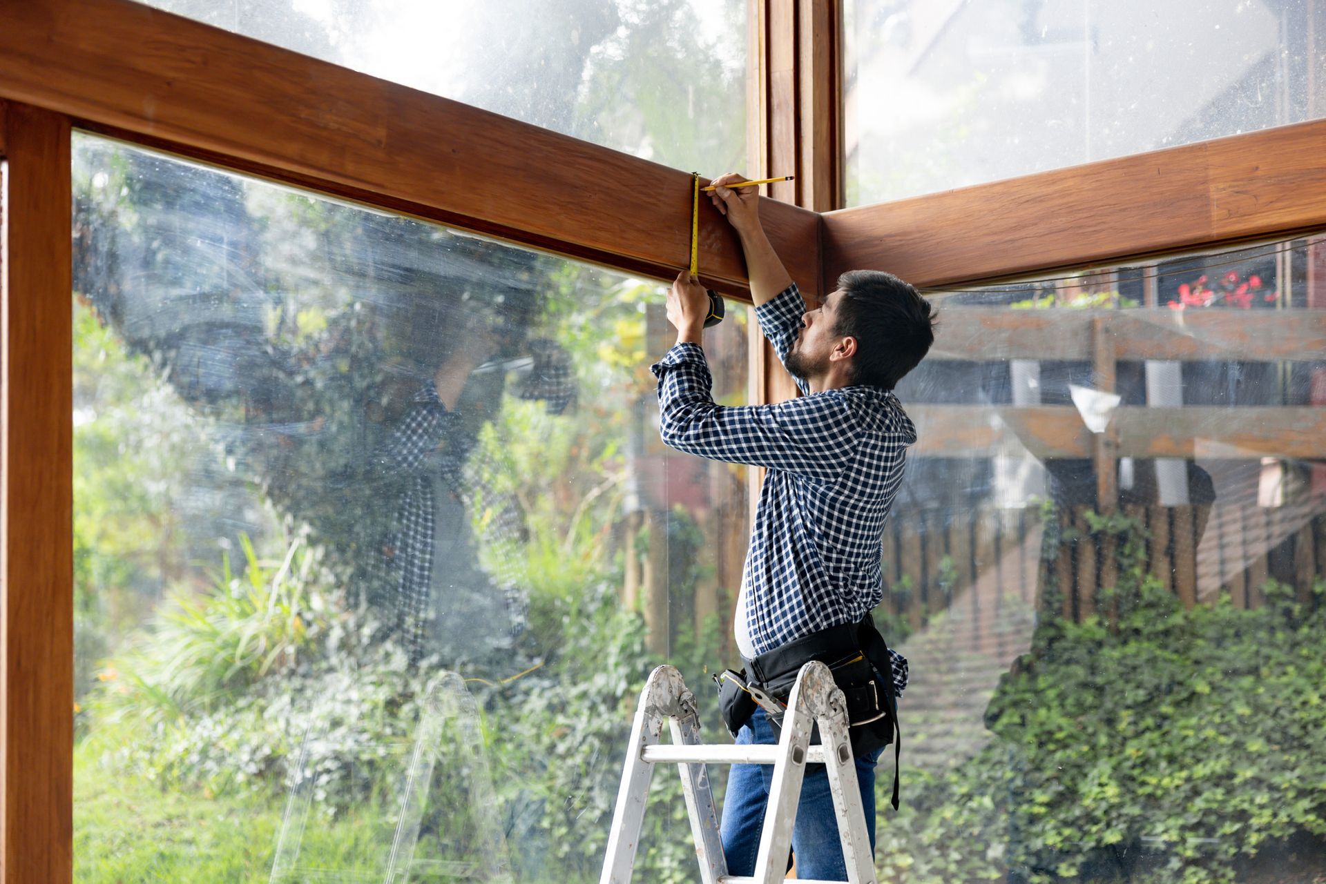 A man is painting a wooden deck with a brush.