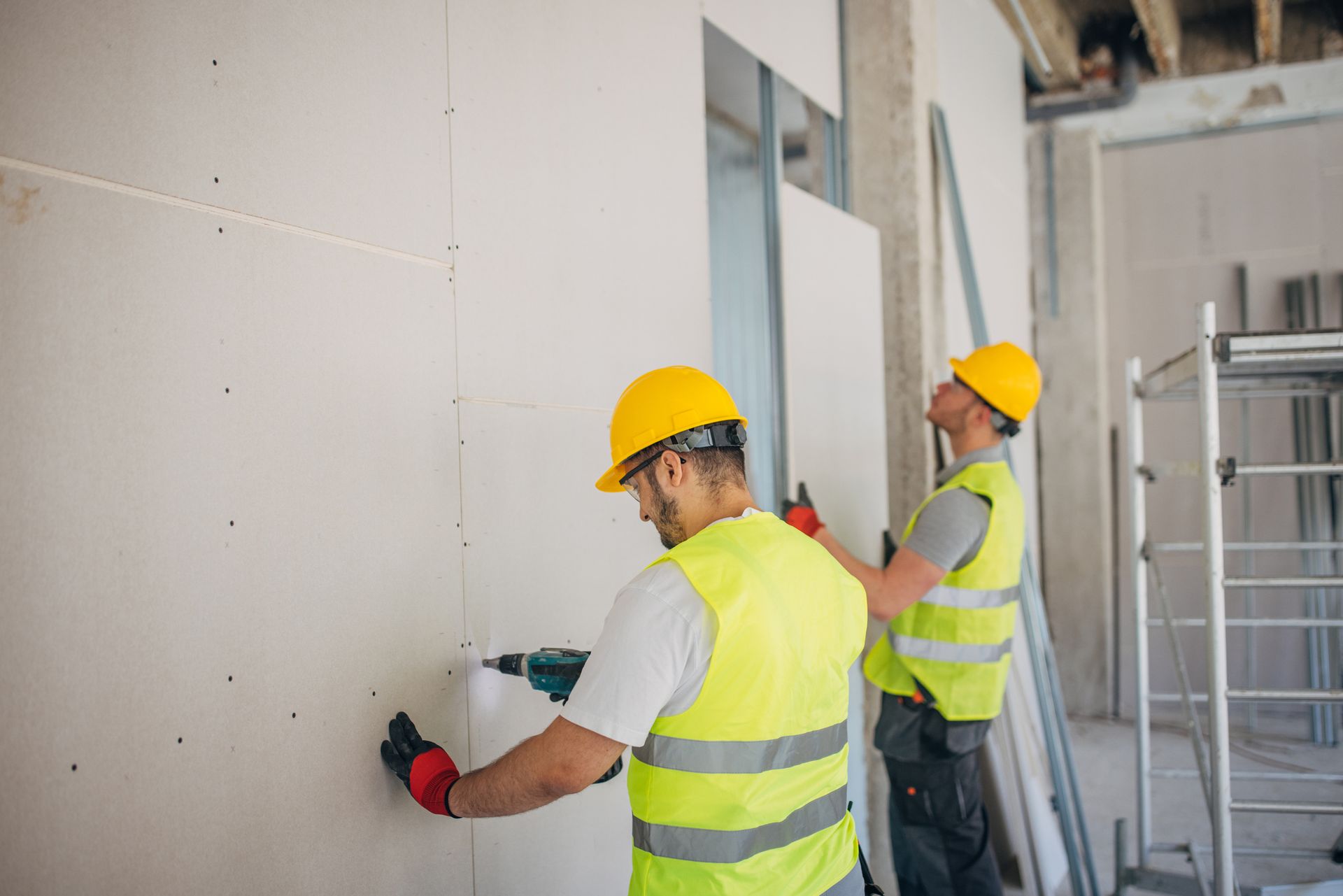 Two construction workers are working on a wall.
