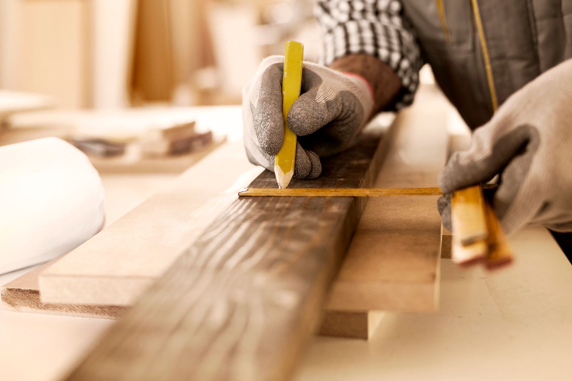 A man is measuring a piece of wood with a tape measure.