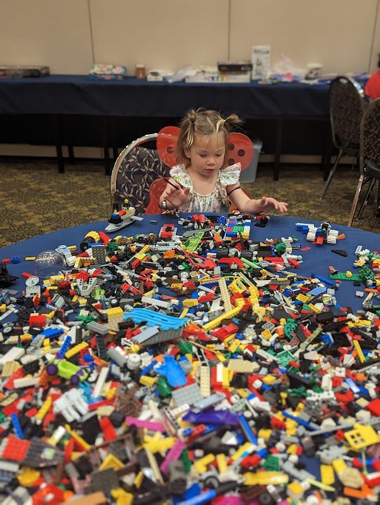 A t.wo year old child sits behind a table full of Legos