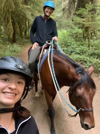 Mother and daughter homeschoolers riding horses on a trail.