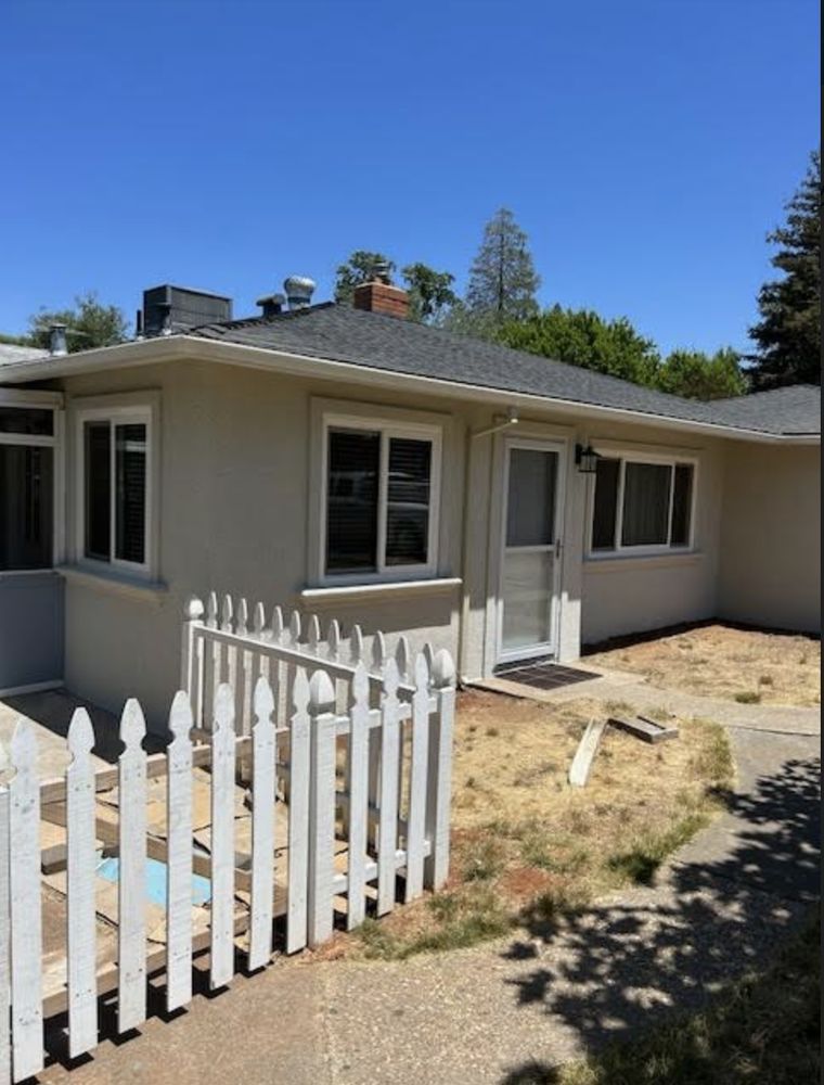Single-story beige house with white trim and a small white picket fence in front
