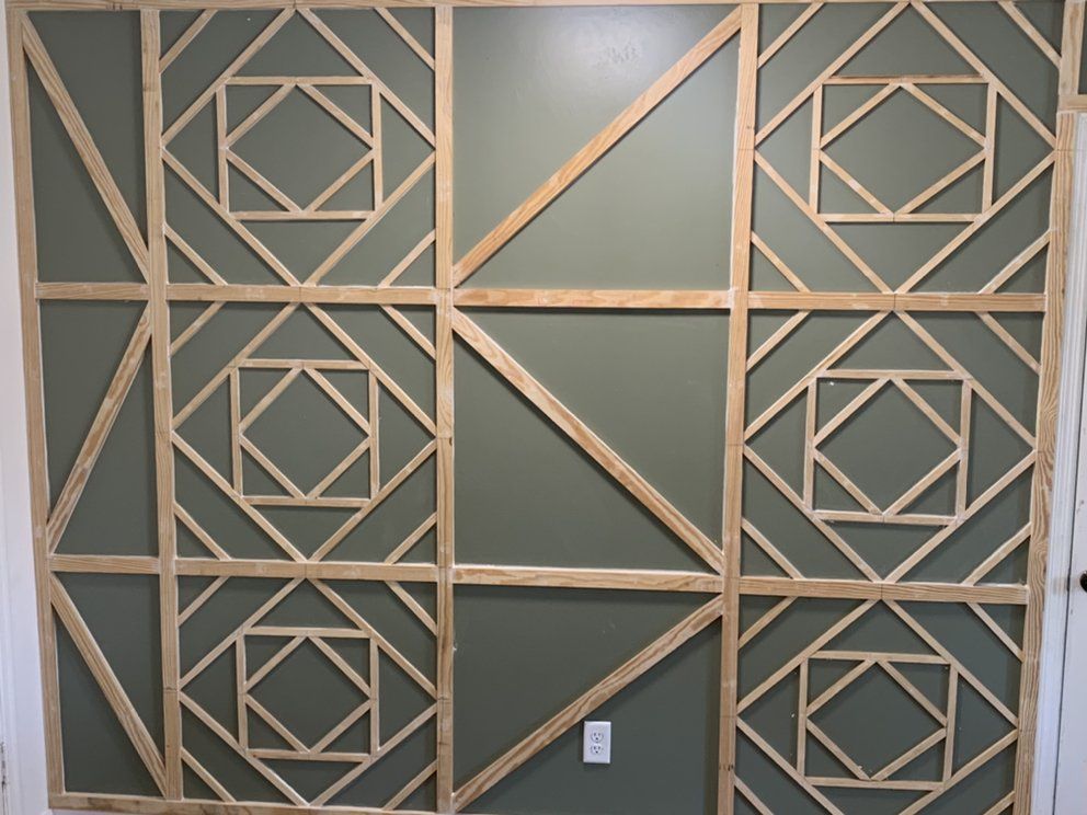 Geometric wood wall art with gold and dark green diamond patterns in a room