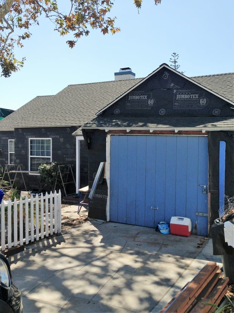 House exterior with a blue garage door, dark siding, and a white picket fence in front yard