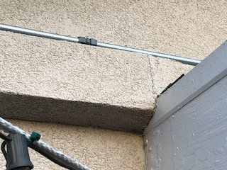 Close-up of a roof gutter and downspout against beige textured walls