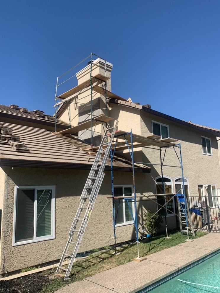 House exterior with ladders and scaffolding beside a swimming pool under a clear blue sky
