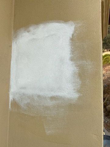 White paint patch on a tan surface with rough, uneven edges