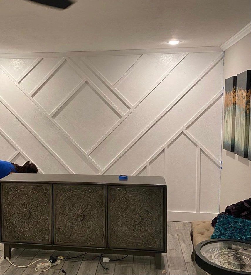 Living room with white geometric wall molding, sideboard, lamp, wall art, and a round coffee table