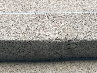 Close-up of a light gray concrete step with a rough texture and shadowed edge