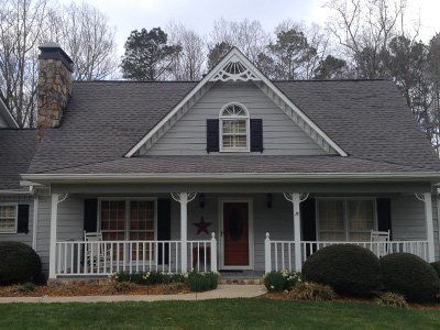 Gray house with white trim, front porch, and red front door beneath a gabled roof